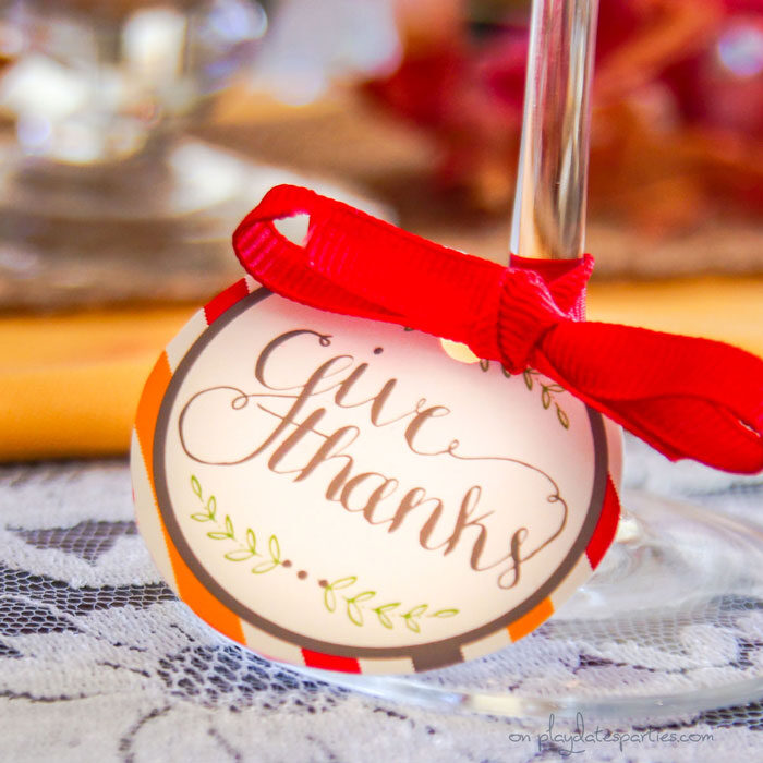 Thanksgiving printable tag on a wine glass stem that reads Give Thanks