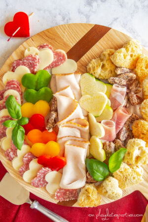 Valentine's Day charcuterie board with heart shaped vegetables, cheese, meat, and croutons