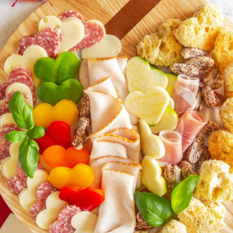 Valentine's Day charcuterie board with heart shaped vegetables, cheese, meat, and croutons