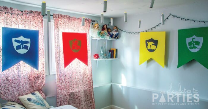 A room with Hogwarts house banners in blue, red, yellow, and green, with floating candles and twinkle lights on the wall