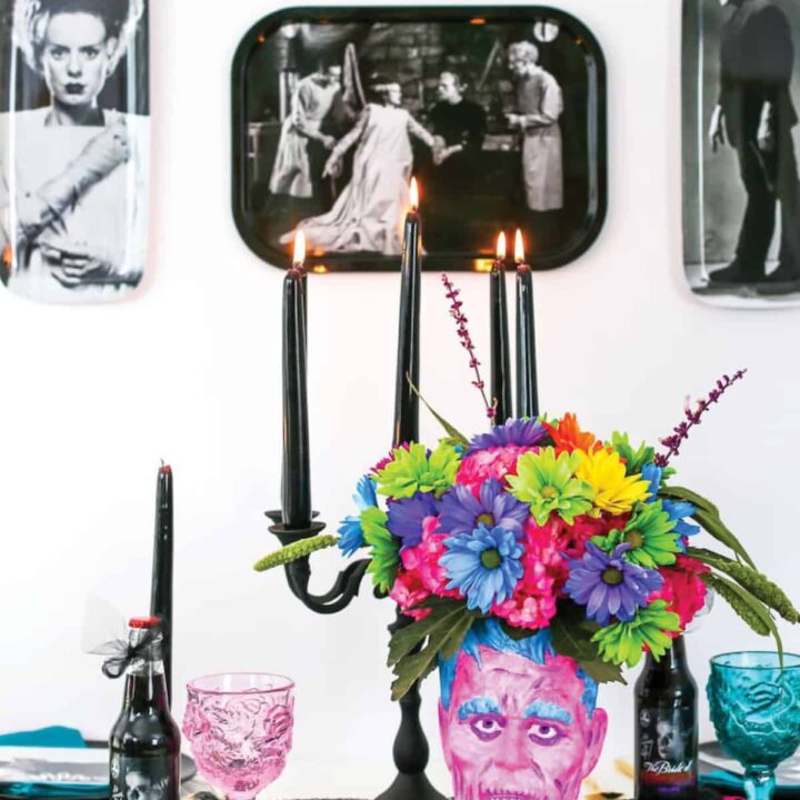 Halloween party with colorful Frankenstein head flower arrangement in front of black and white decorations