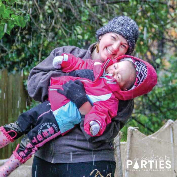 A young woman and her 2 year old daughter playing in a light snowfall