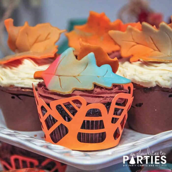 chocolate cupcakes with a candy corn wrapper and multi-colored fall leaf fondant toppers