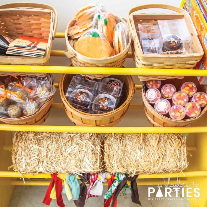 Yellow treat display with mini hay bales, bushel baskets and berry baskets filled with sweet treats