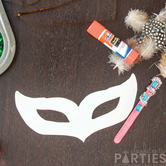 image of a blank mask template on a table surrounded by decorative supplies