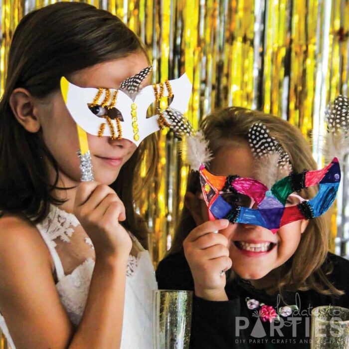 girls dressed up holding finished masks to their faces.