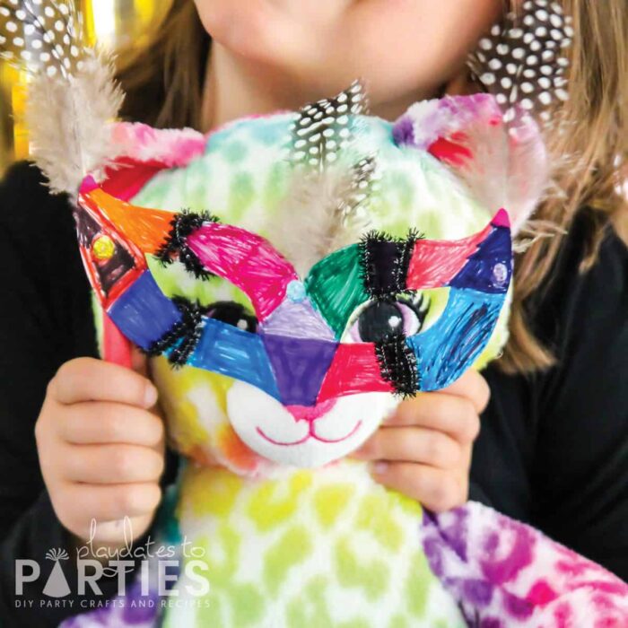 Child holding a decorated mask to a stuffed bear's face