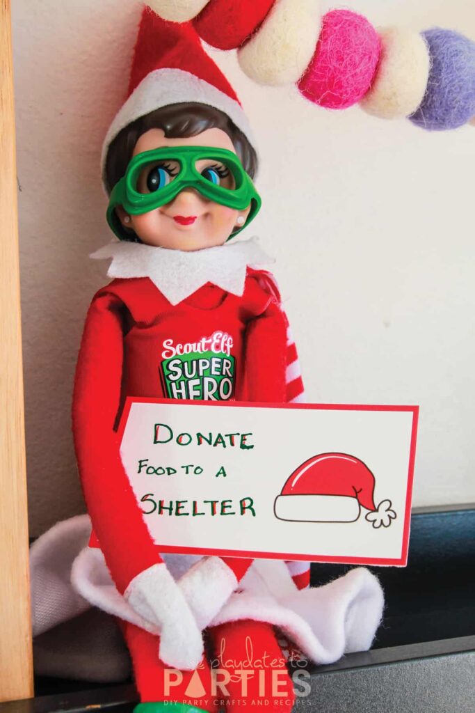 photo of elf on the shelf sitting on a ledge holding a card with a handwritten message