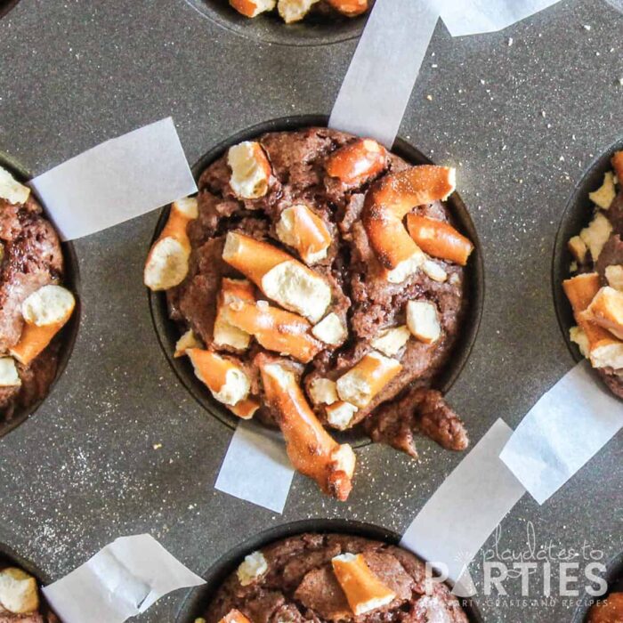 close up of brownie bites in a muffin tin with parchment strips coming out from under the baked brownie