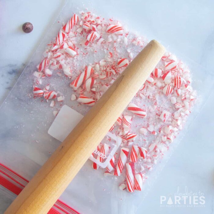 candy cane pieces in a zip top bag being crushed with a rolling pin