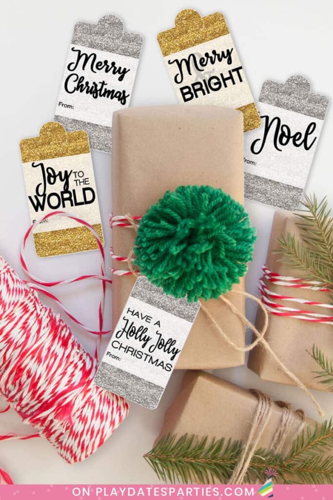 brown paper packages tied with red bakers twine and a green pompom with gold and silver glitter holiday gift tags