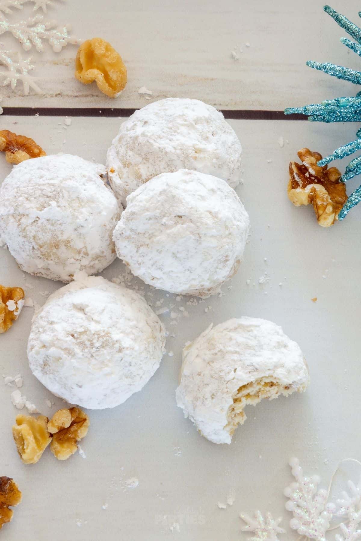 Powdery Russian tea cakes - also known as snowballs - are on a white wood surface.