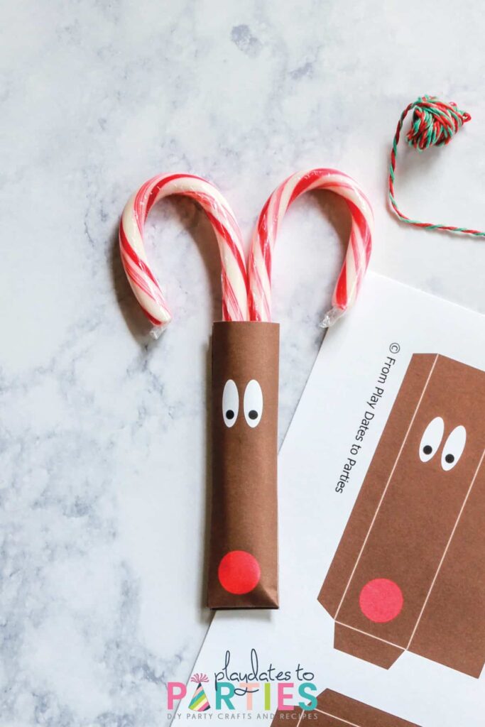 finished reindeer candy cane pocket on a marble table with a twine and a printed paper