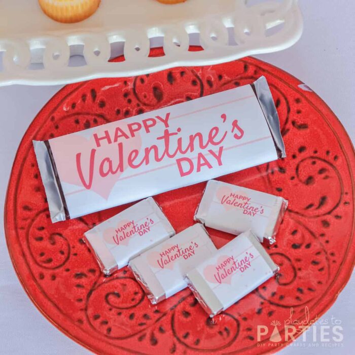 Full sized and mini candy bars with custom wrappers on a red plate