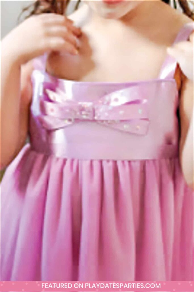 close up of a little girl's purple dress with a tutu skirt and a purple and white polka dot bow on front