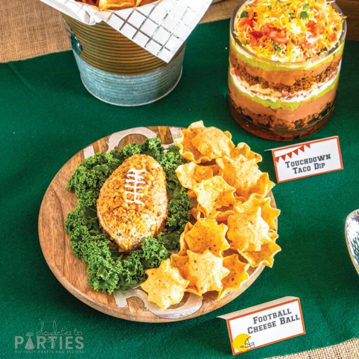 wood tray with a football shaped cheese ball on a green felt table topper