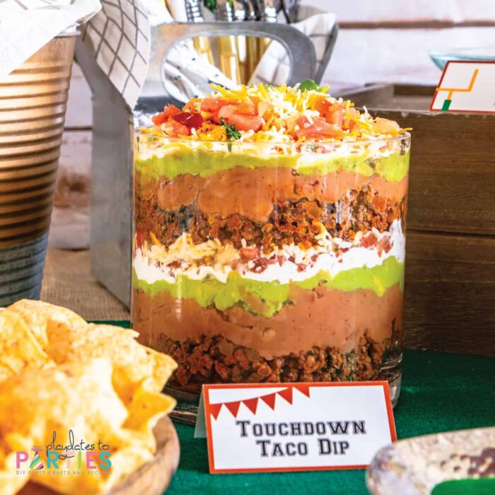 layered dip in a glass bowl with a printable party label that says touchdown taco dip