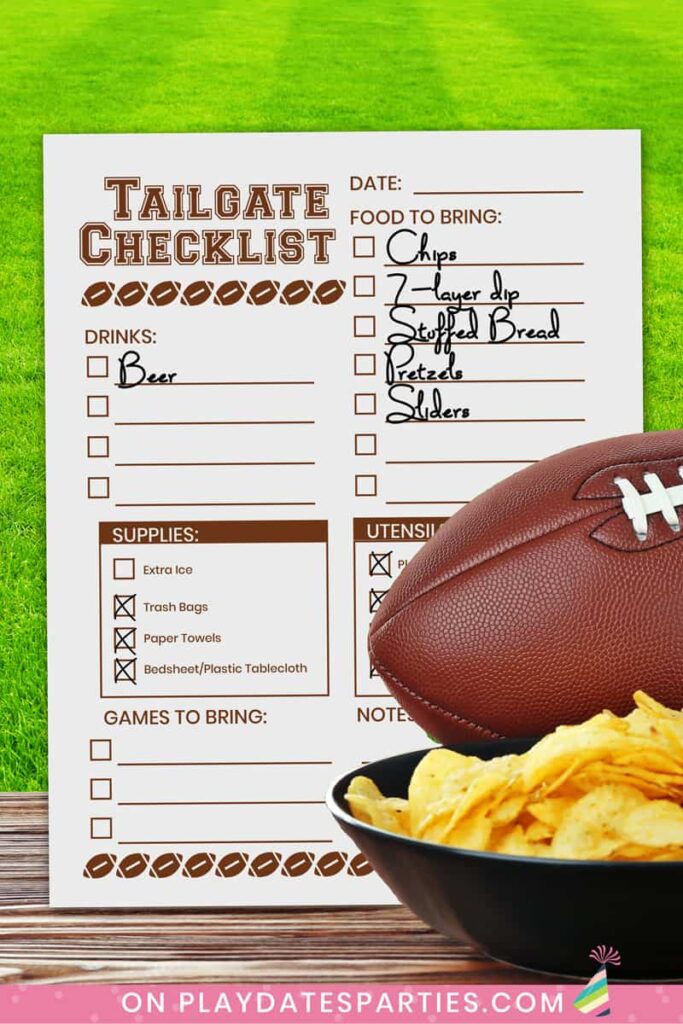football and bowl of chips on a table in front of a field and a tailgate checklist that is partially filled in.
