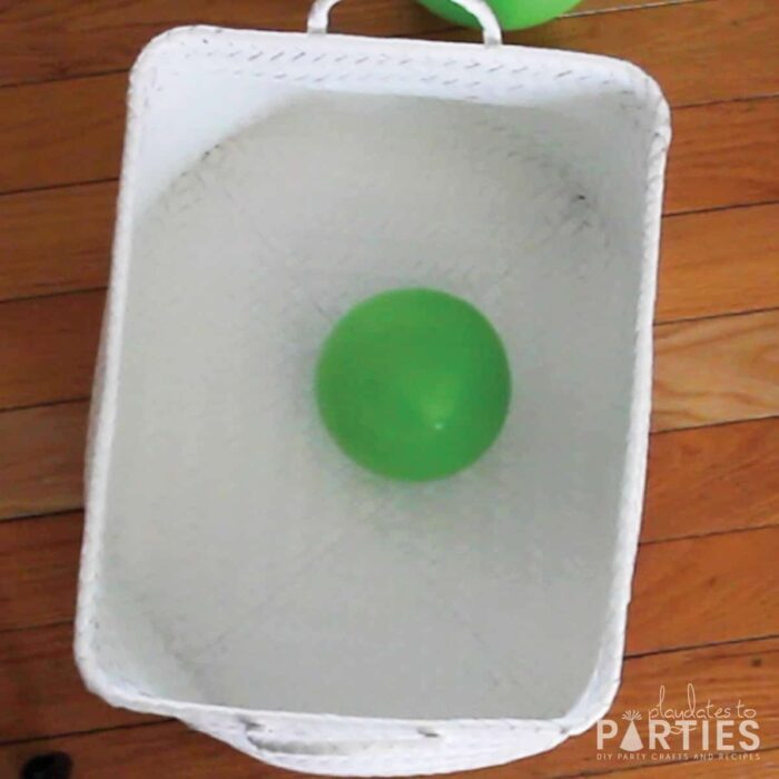 a green balloon laying in a white basket