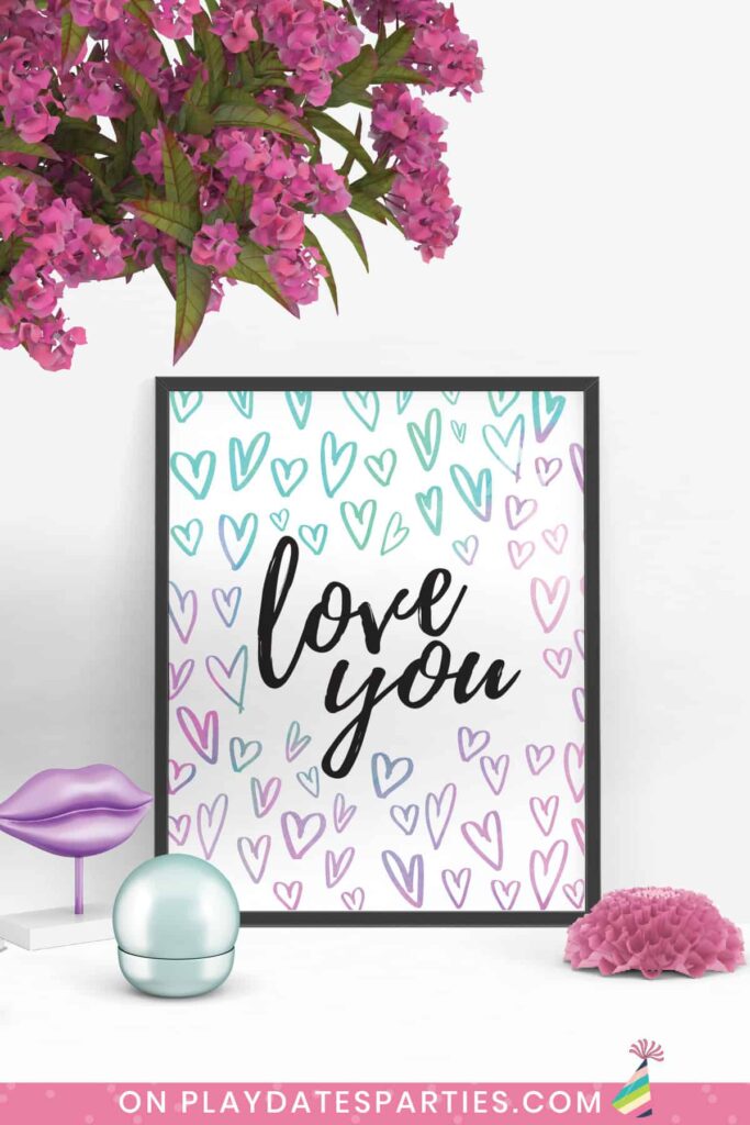 framed print of the words love you in black script surrounded by hearts in watercolors ranging from pink to purple to aqua.