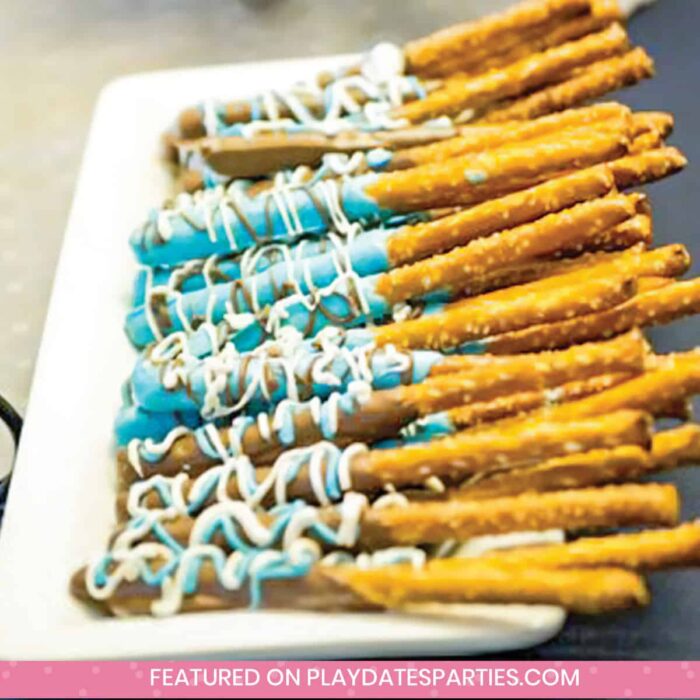 a plate of pretzel rods dipped in chocolate and blue candy melts drizzled with white and blue chocolate