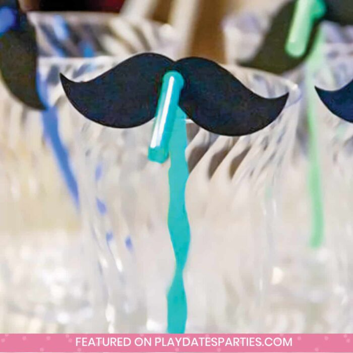 clear plastic cups with colorful blue and green straws and black paper mustache decorations on the straws