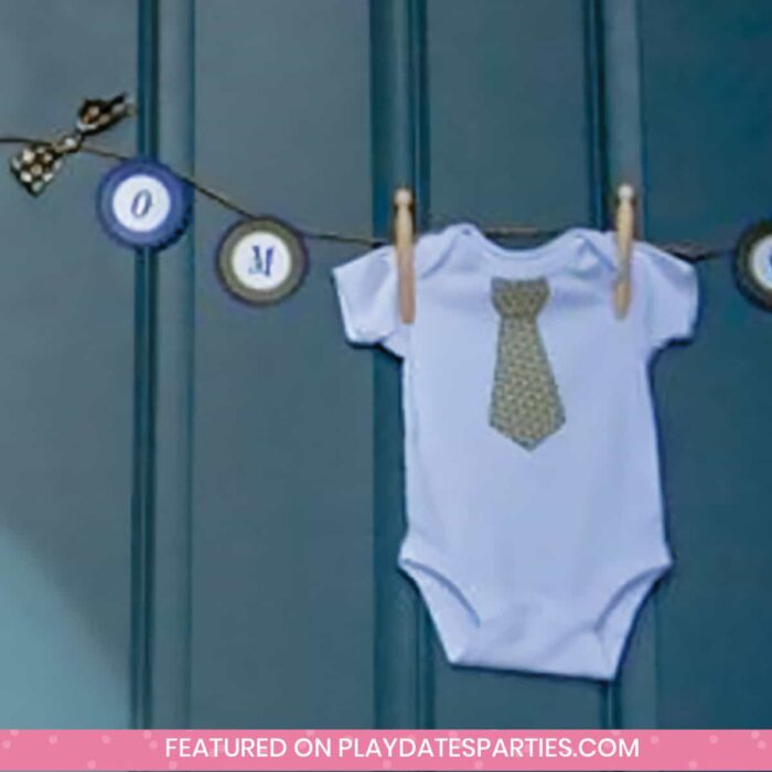 baby onesie with a necktie hanging as decoration on a party banner