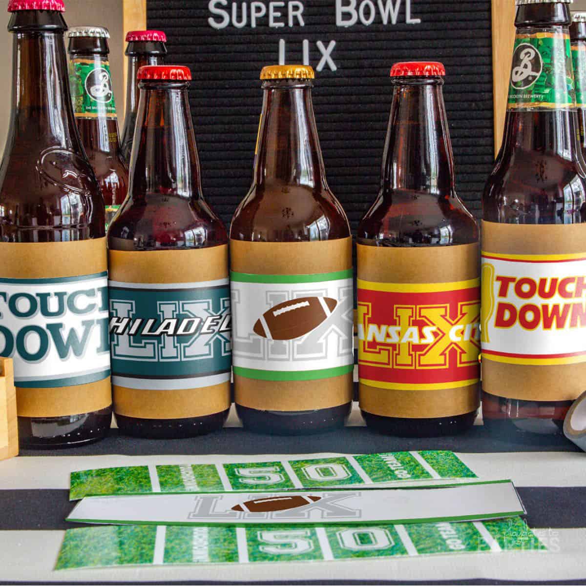 five beer bottles in a row on a table wrapped with football labels