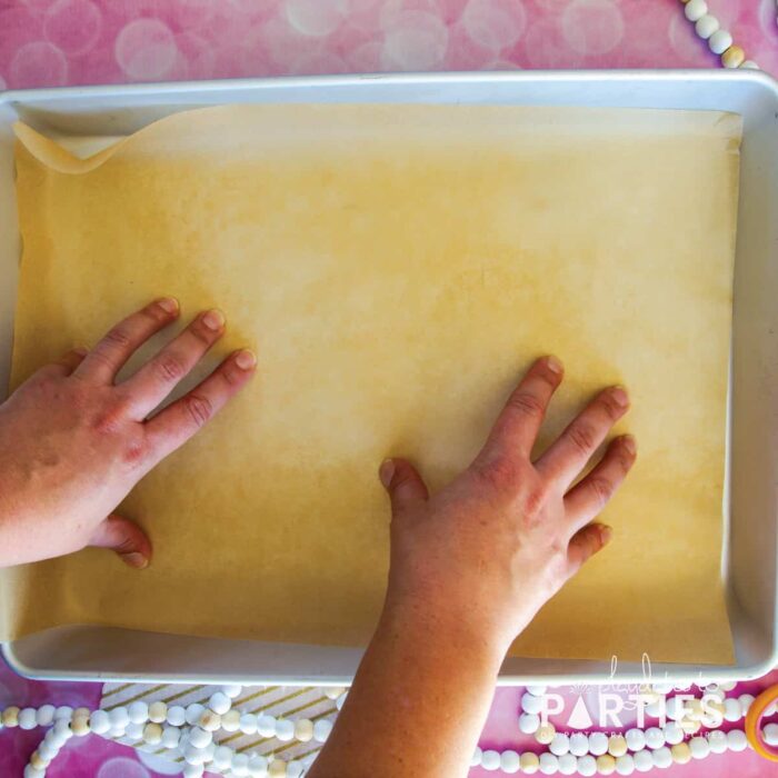 placing a sheet of parchment paper in the bottom of a baking pan