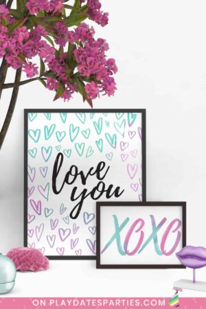 two watercolor Valentine's Day art prints on a white table in black frames