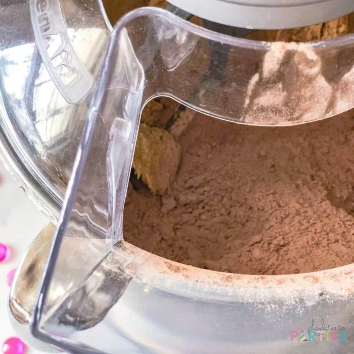 closeup of a stand mixer with splash guard and cocoa powder splashed inside