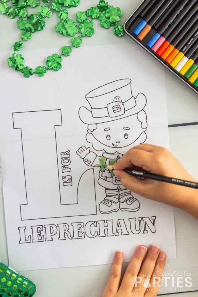 overhead image of a child coloring a sheet with a picture of a Leprechaun that says L is for Leprechaun