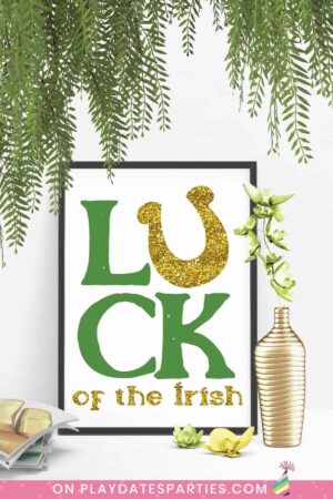 framed copy of Luck of the Irish print on a white floor with a vase and flowers in front of it.