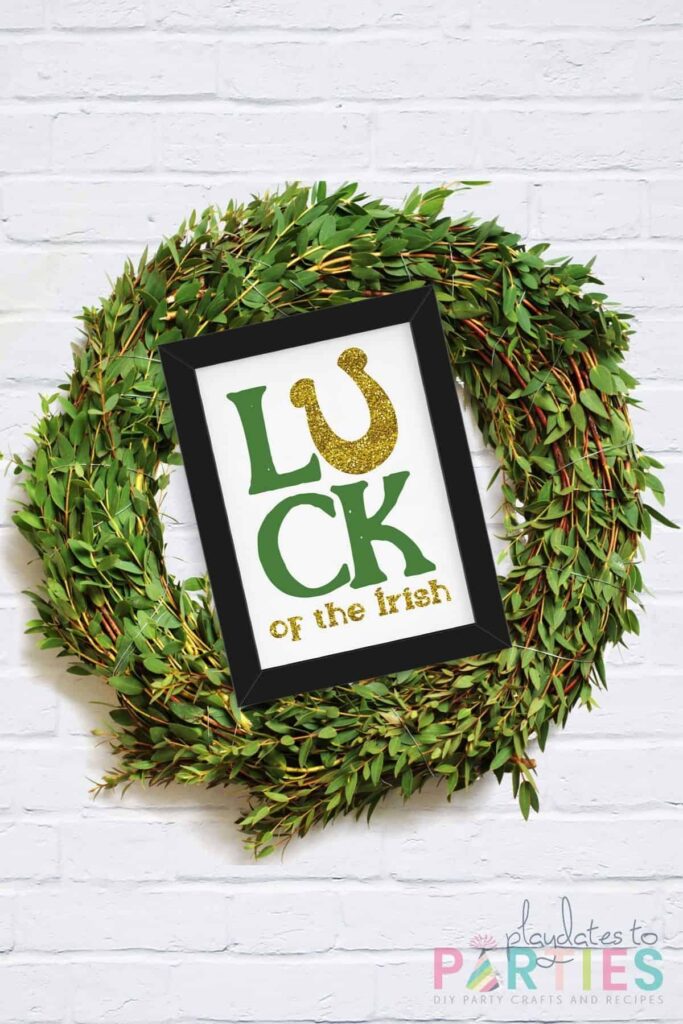 wreath on a white brick wall with a sign that says Luck of the Irish attached to the front.