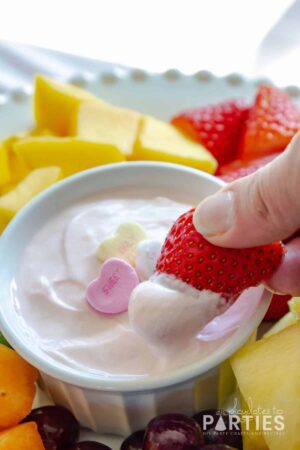 half a strawberry dipped into pink fruit dip with Valentine candy on top