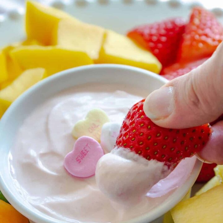 half a strawberry dipped into pink fruit dip with Valentine candy on top