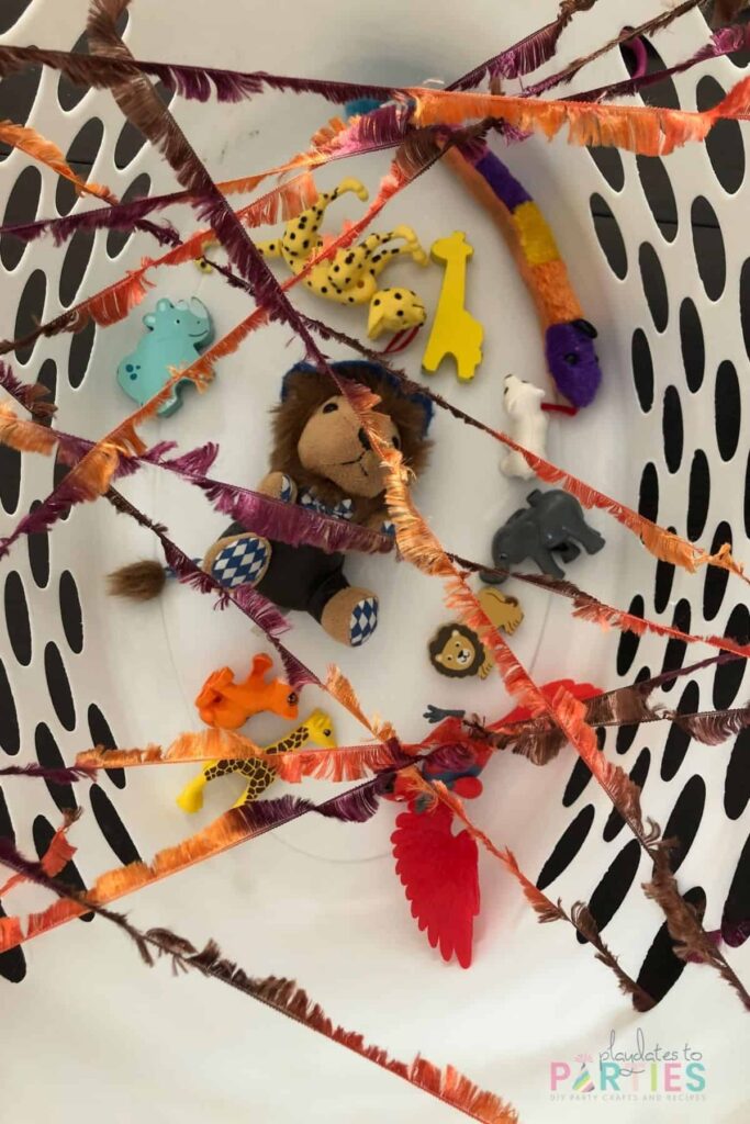 overhead view of laundry basket with toys inside and yarn woven across the top