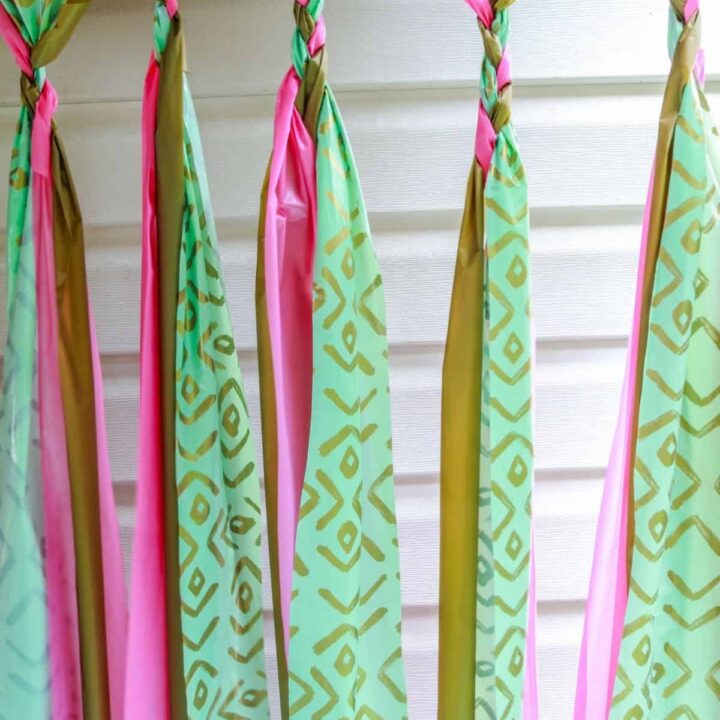 party backdrop made with a gold plastic tablecloth, a pink plastic tablecloth, and a patterned gold and aqua plastic tablecloth