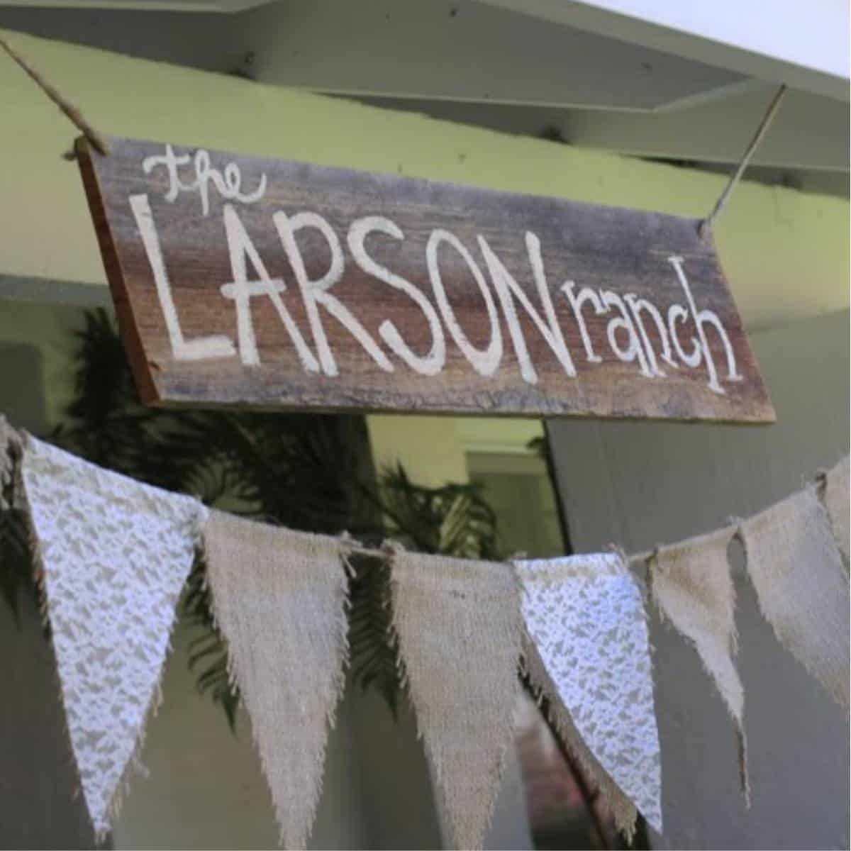 Handmade wooden sign that says "The Larson Ranch" over bunting made with burlap and lace