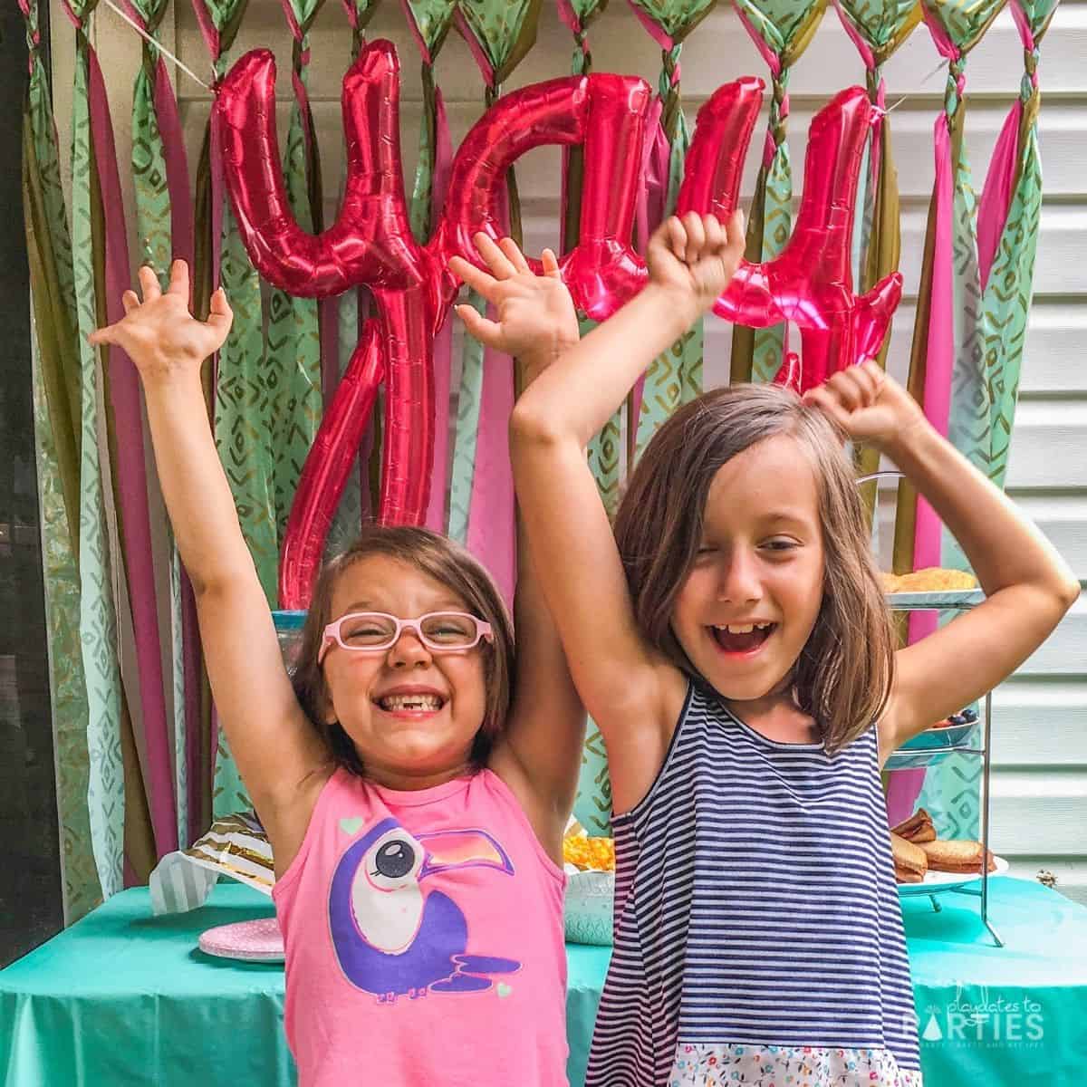 two girls in front of a party table with a "yay" balloon celebrating the last day of school