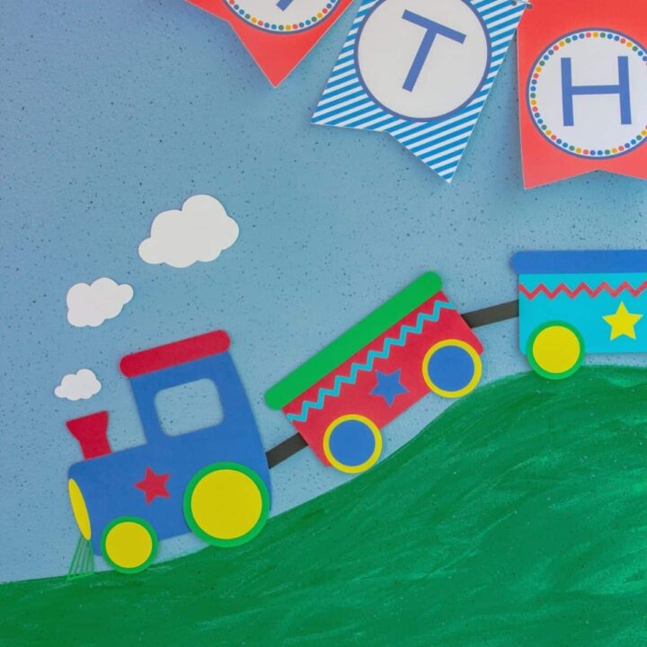 Close up of 2 dimensional paper train on a blue backdrop that looks like it's rolling down a hill.
