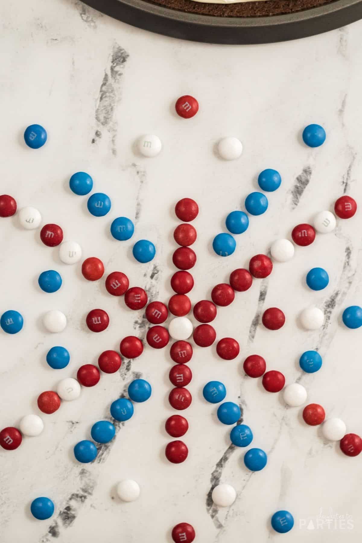 Red white and blue candies arranged on a marble counter before being placed on frosting