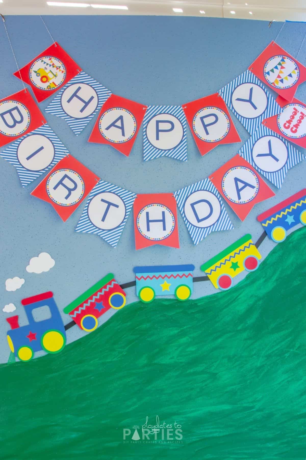 finished train party backdrop with a paper train, and happy birthday banner