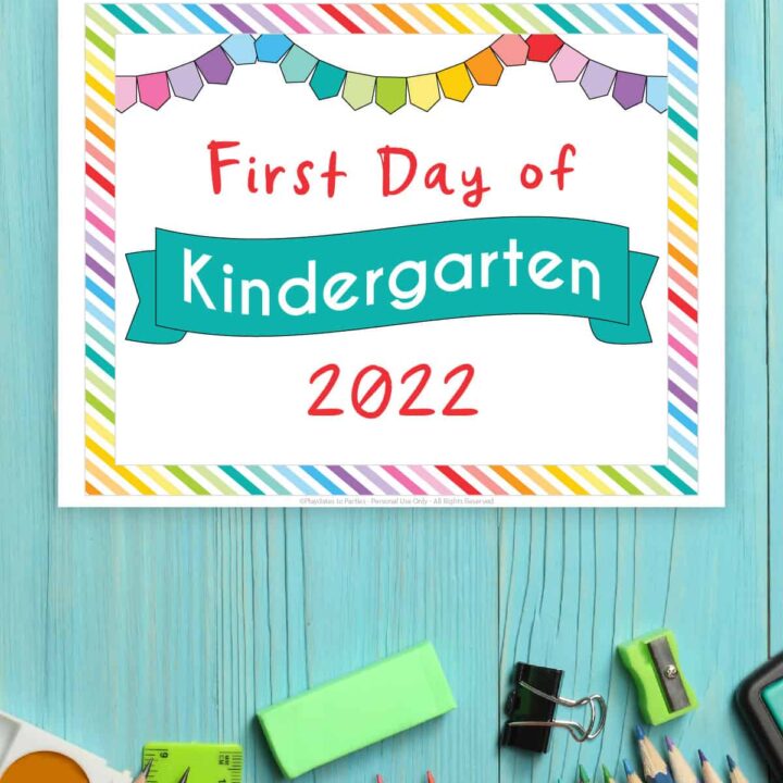 colorful page with a rainbow border on a blue table that says first day of Kindergarten