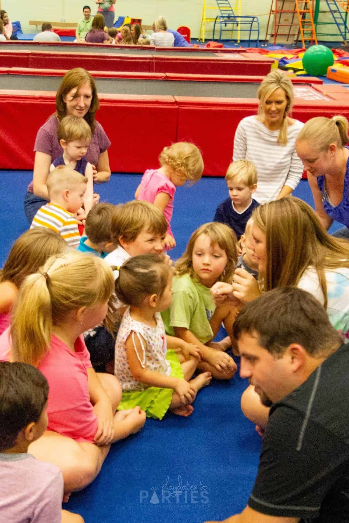 children sitting at a play gym with an instructor leading group play