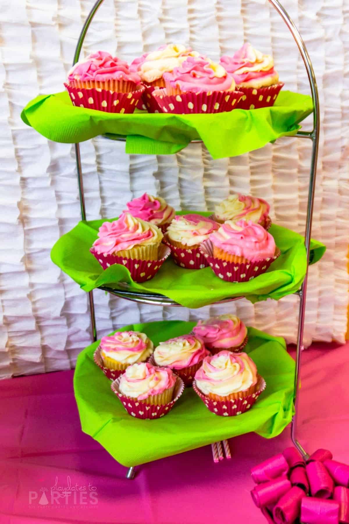 cupcakes on a three tiered tray with white and pink swirl frosting and pink cupcake liners with white polka dots