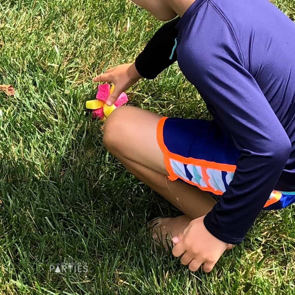 a toddler boy playing in the summer sun with water toys