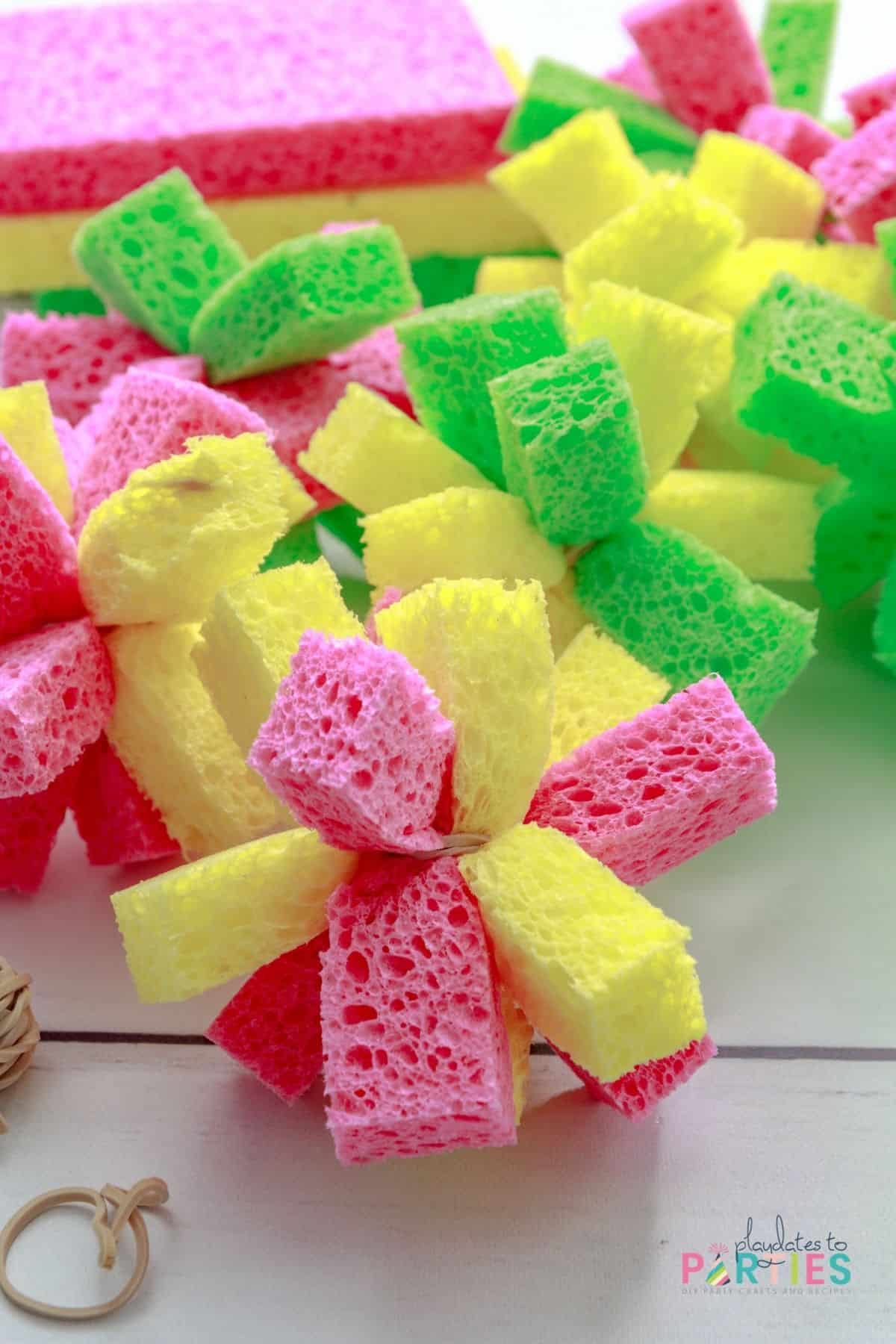 colorful sponge balls on a table in front of a pile of sponges