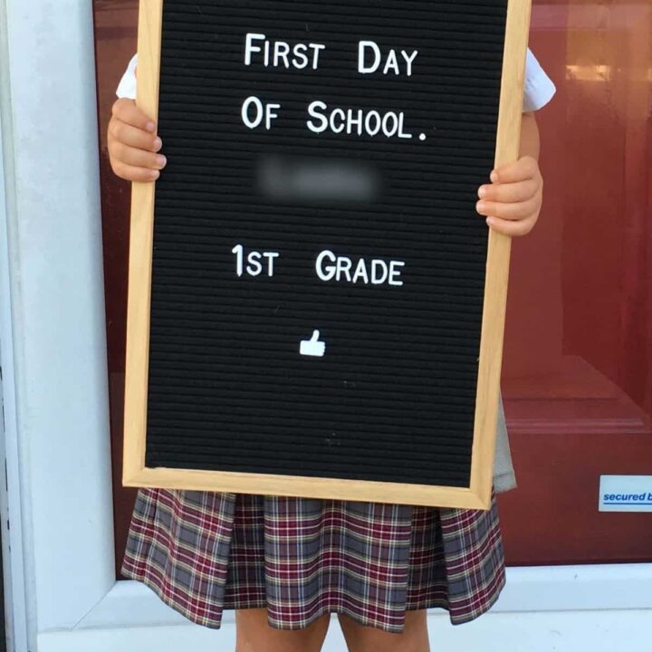 little girl holding up a letter board sign that says first day of school 1st grade