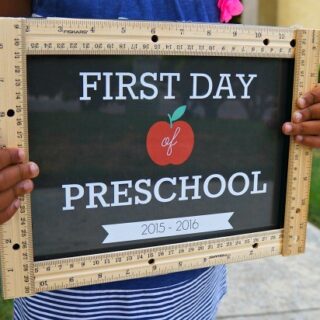 close up of a child holding a sign with rulers that says first day of preschool